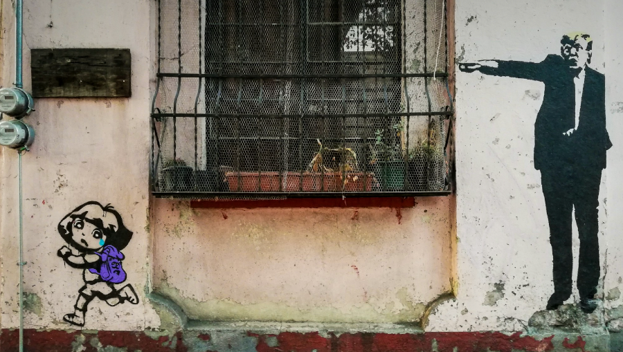 Illustration on a building of Trump ordering a cartoon child to run away.